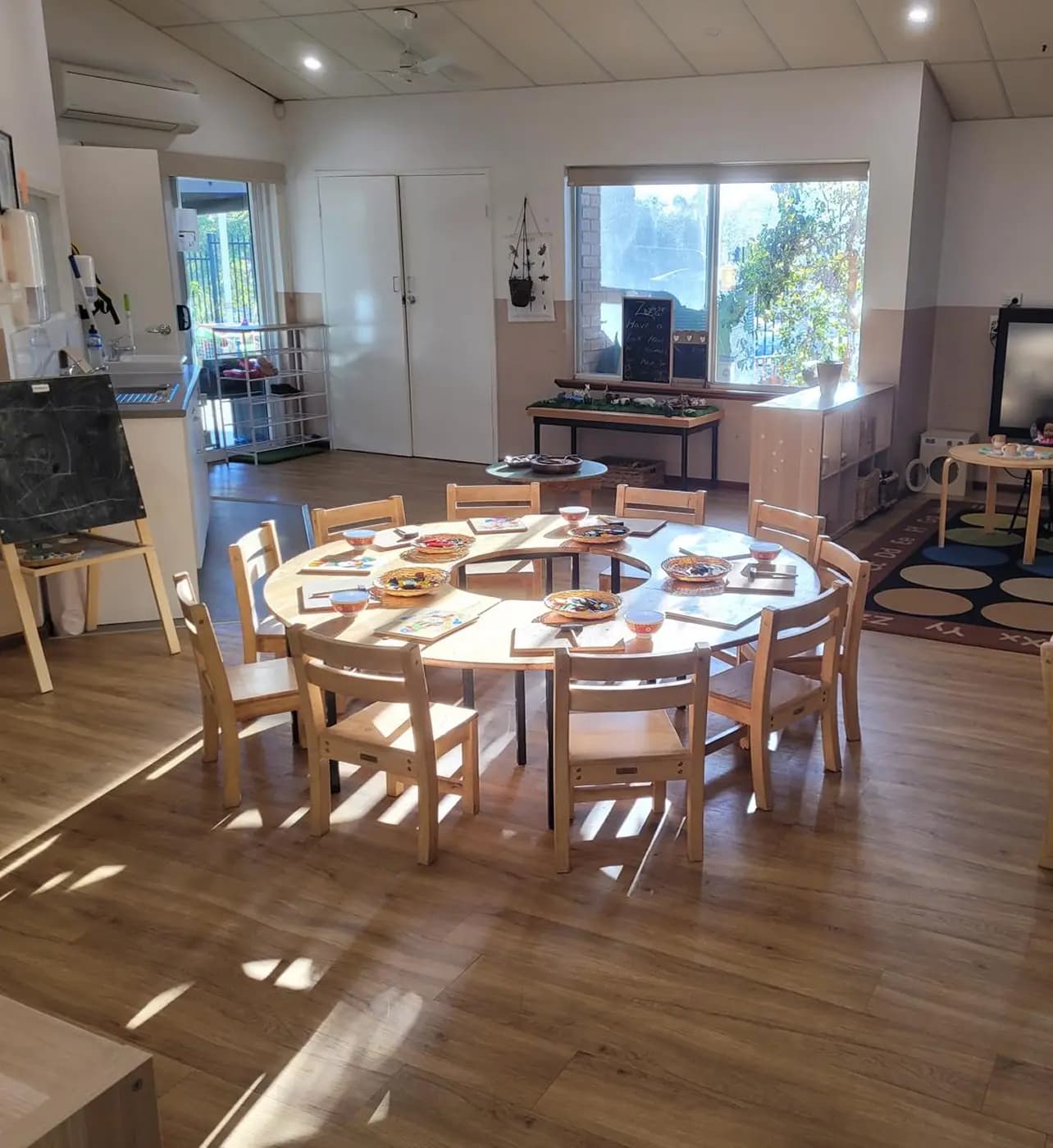 Bright Moolanda early learning classroom with round wooden tables prepared for play-based activities, showcasing a welcoming and child-safe environment.