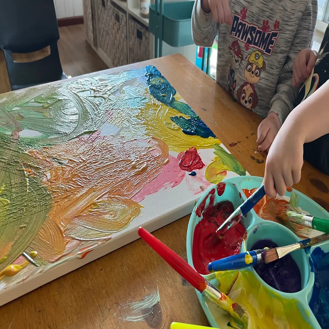 Children enjoying painting on canvas as part of a play-based early childhood learning activity.